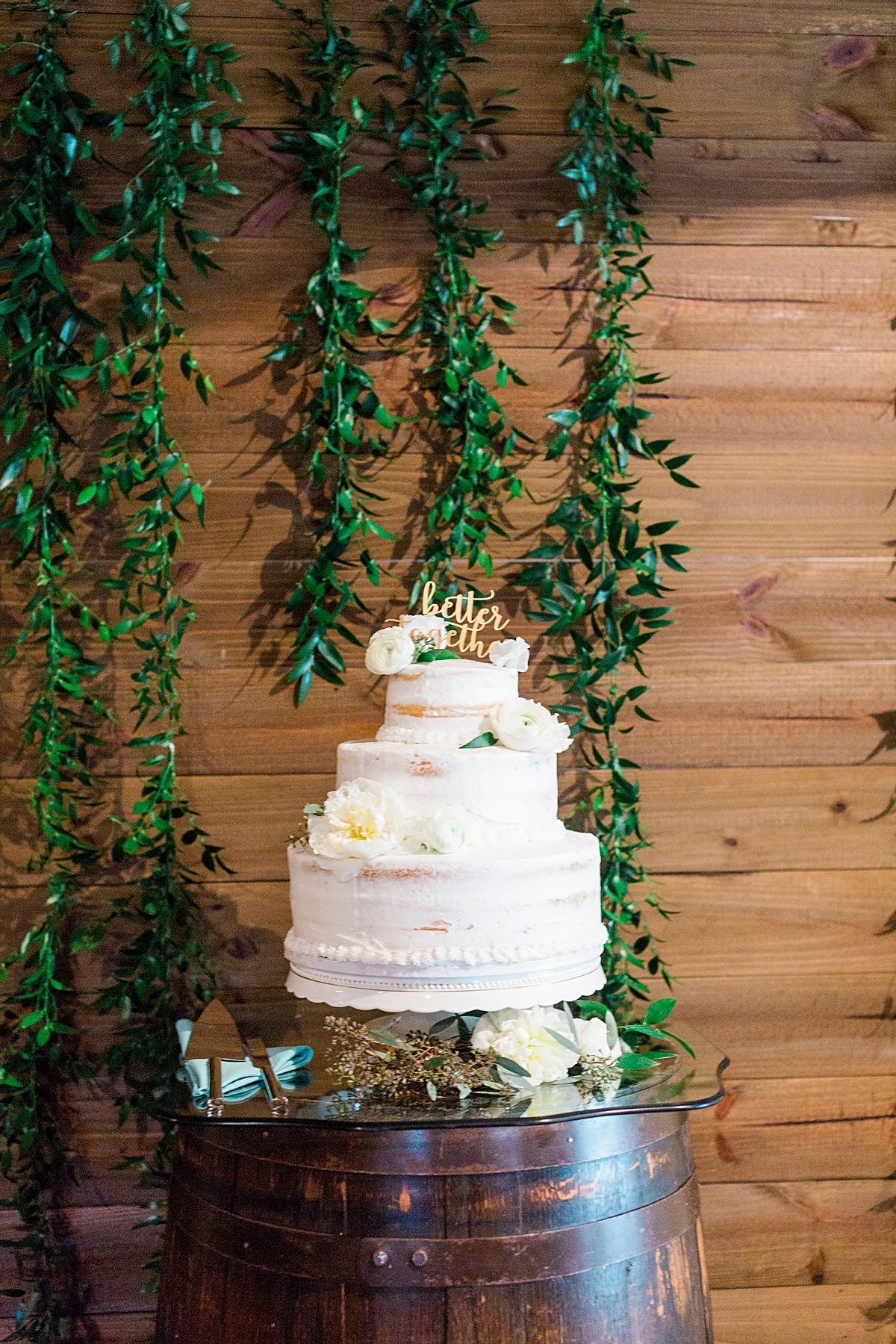rustic wood pallet backdrop with hanging greenery for wedding cake display table 