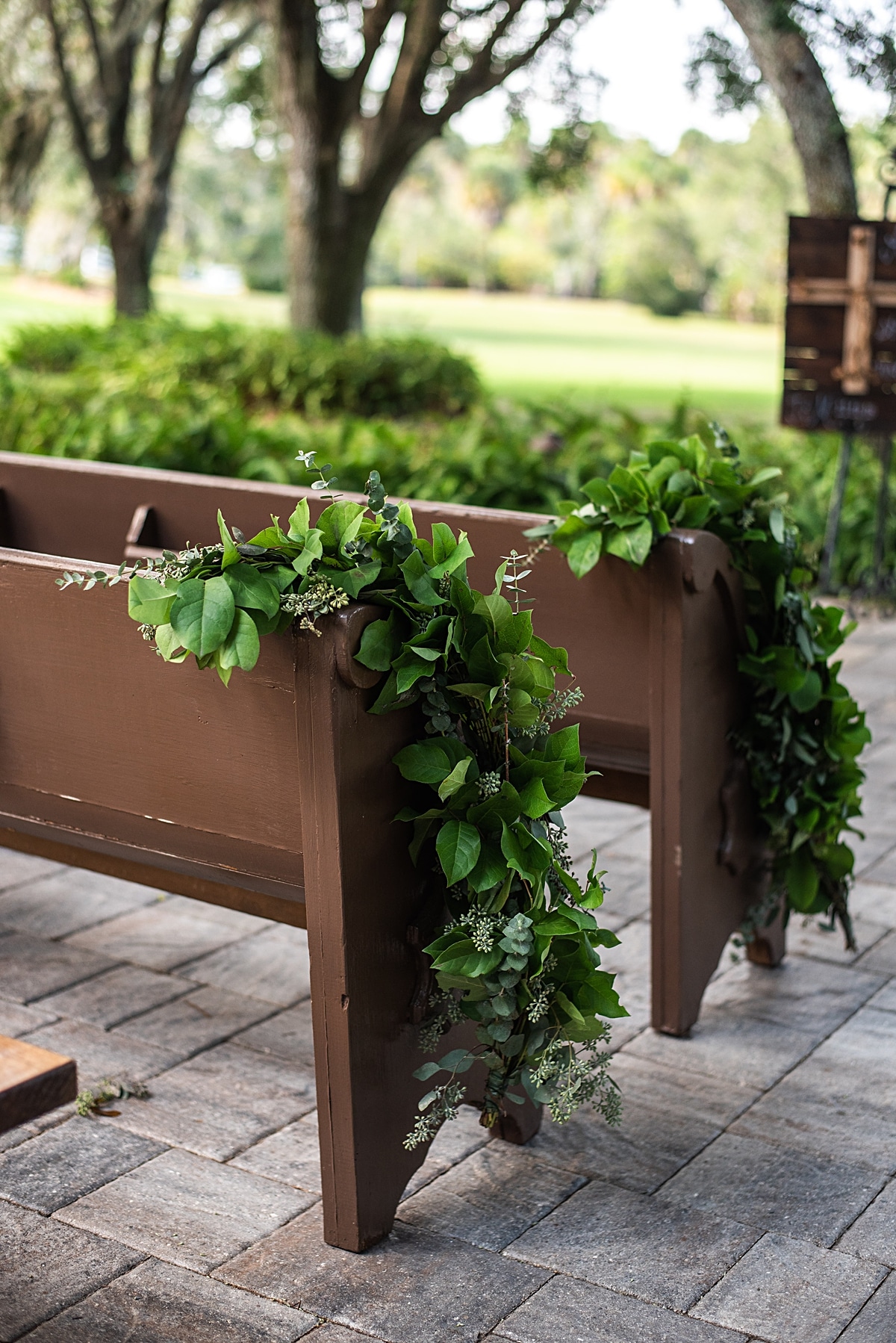 Greenery runners accenting classic wooden pews for outdoor wedding ceremony 