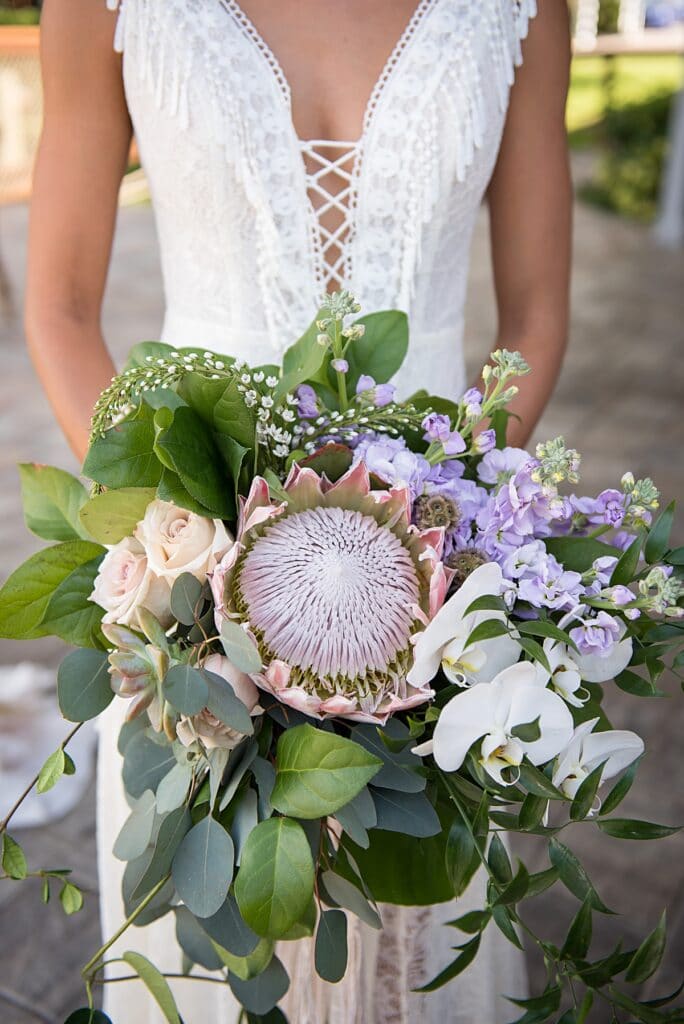 earthy boho bride with plunging neckline and king protea bridal bouquet