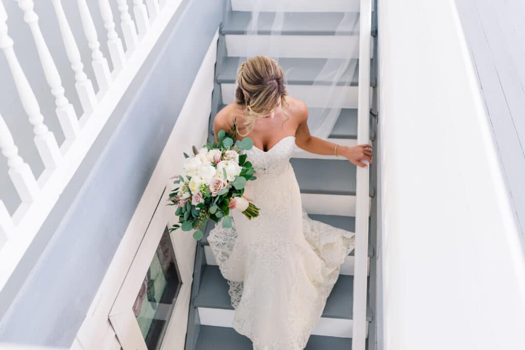 Brevard County bride walking downstairs in the decklan house with flower bouquet