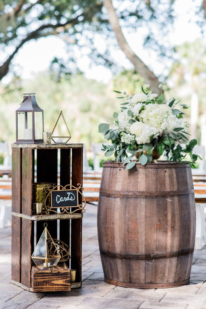 Antique crate decor doubles as a card display alongside vintage whiskey barrel in this rustic outdoor ceremony