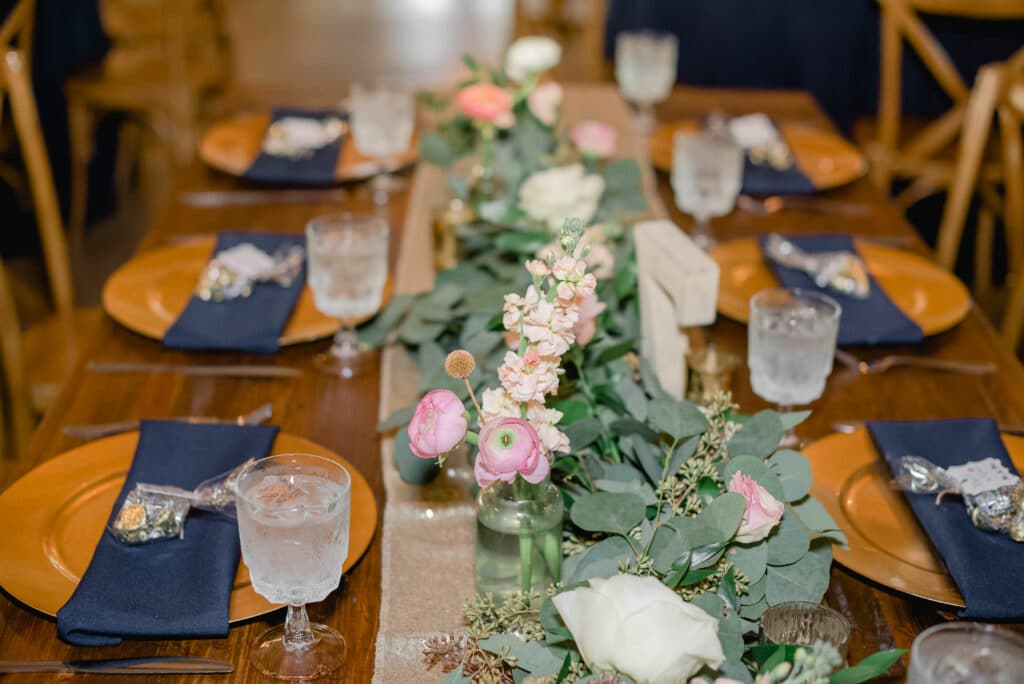 Charming, rustic reception centerpieces with seeded eucalyptus greenery table runners and delicate blooms