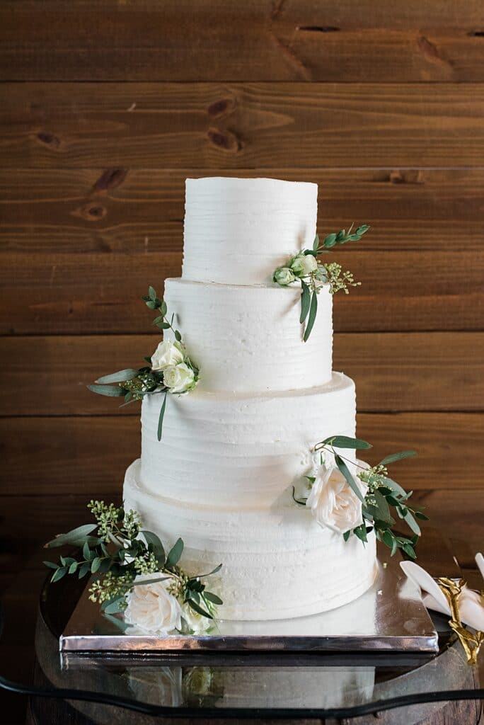 White buttercream 4-tiered wedding cake from the cake lady with seeded eucalyptus greenery accents