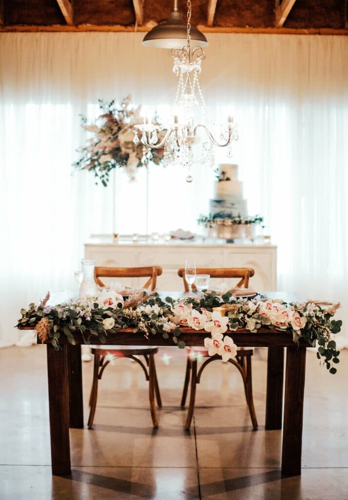 Funky bohemian sweetheart table design with eucalyptus and tropical white flowers