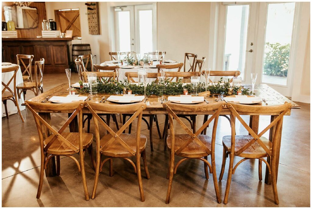 Rustic farm tables with greenery runners and glass candle votives