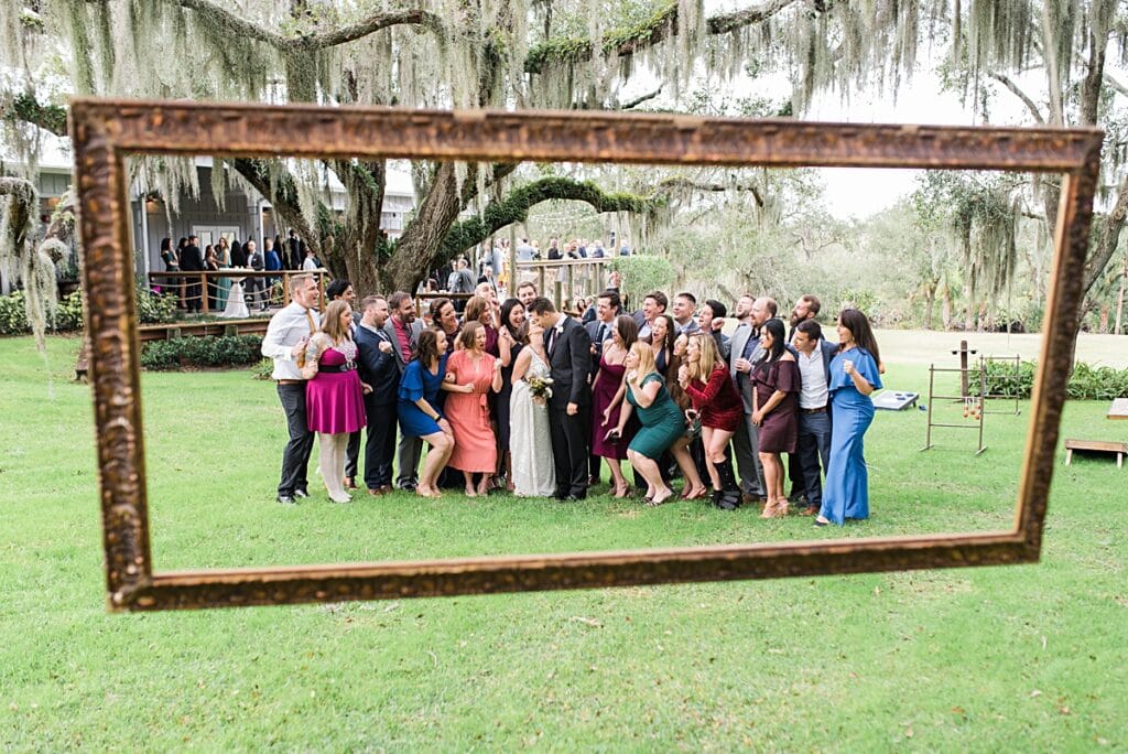 Wedding guest group shot featuring a hanging gilded frame rental