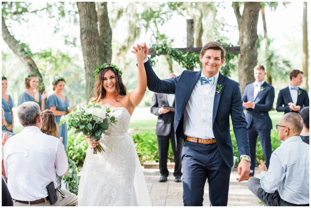 classic greenery style outdoor wedding ceremony with custom wood cross and greenery crowns