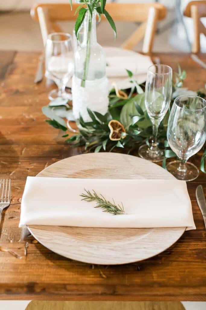 Driftwood chargers and rosemary accents for wedding tablescape